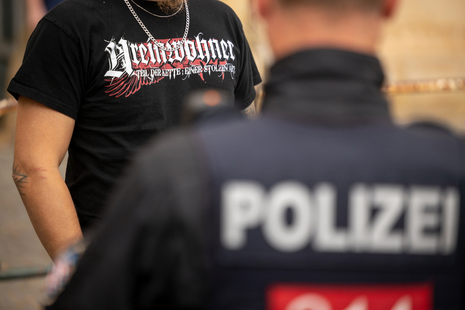 Ein Teilnehmer einer von einem NPD-Funktionär angemeldeten Demonstration trägt ein T-Shirt mit der Aufschrift "Ureinwohner" während er von einem Polizisten kontrolliert wird. (Symbolbild)