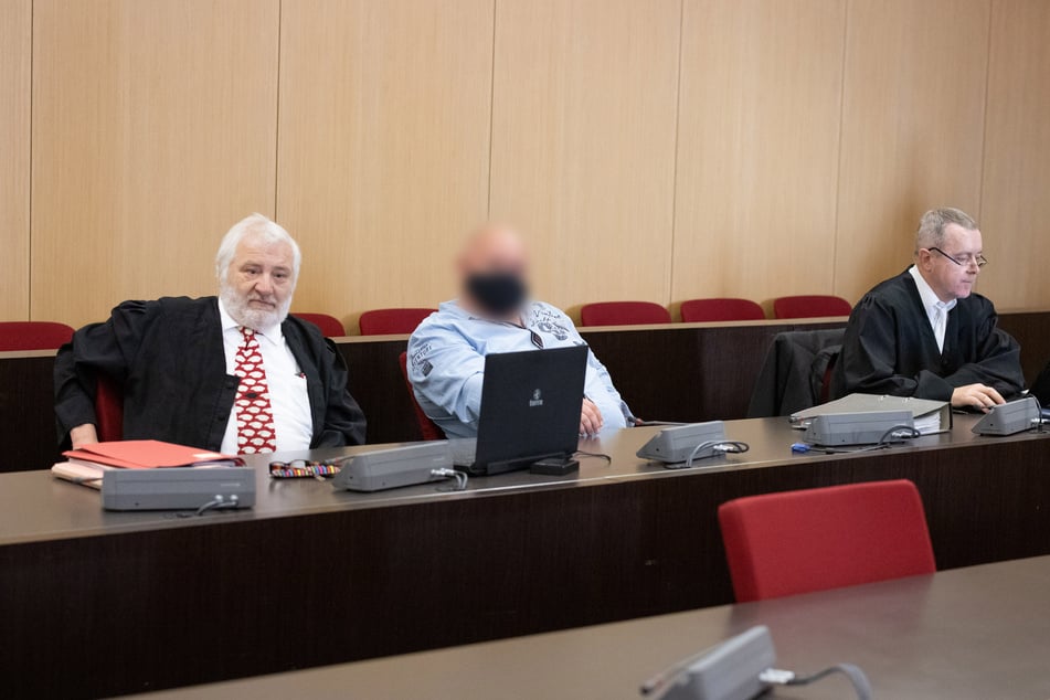 Der Angeklagte (M) sitzt zwischen seinen Anwälten in einem Saal des Düsseldorfer Landgerichts.
