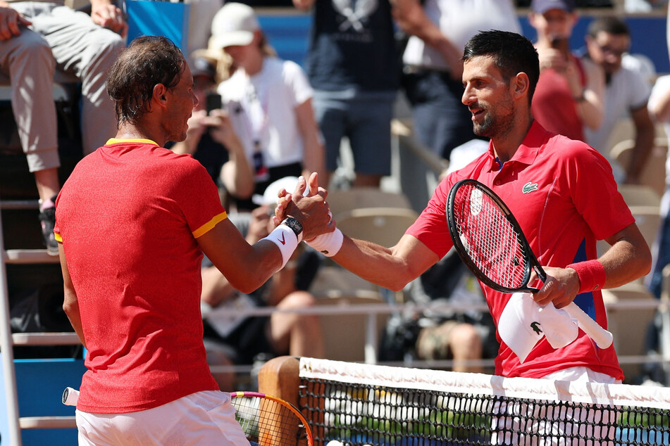 Novak Djokovic of Serbia (r.) and Rafael Nadal of Spain shake hands after their match during the 2024 Paris Olympics at Roland Garros Stadium.