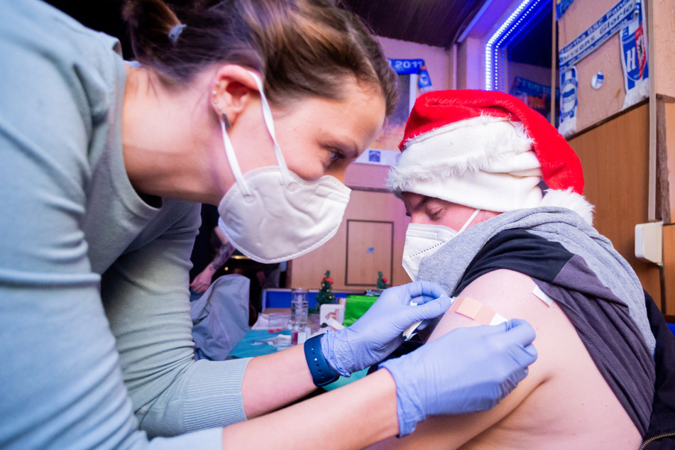 Ein Mann mit Weihnachtsmannmütze lässt sich in der Berliner Kneipe "Berlinchen" mit Biontech gegen Corona impfen.