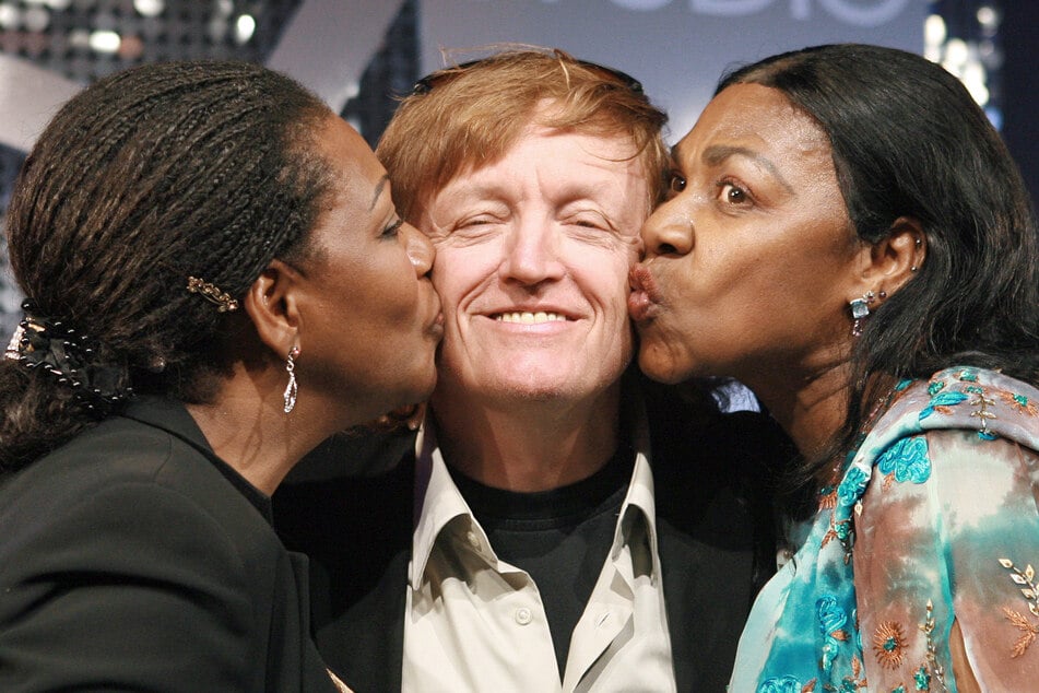 Die ehemaligen Sängerinnen der Gruppe Boney M., Liz Mitchell (l.) und Marcia Barrett, küssen Farian auf der Premiere des Musicals "Daddy Cool". (Archivbild)