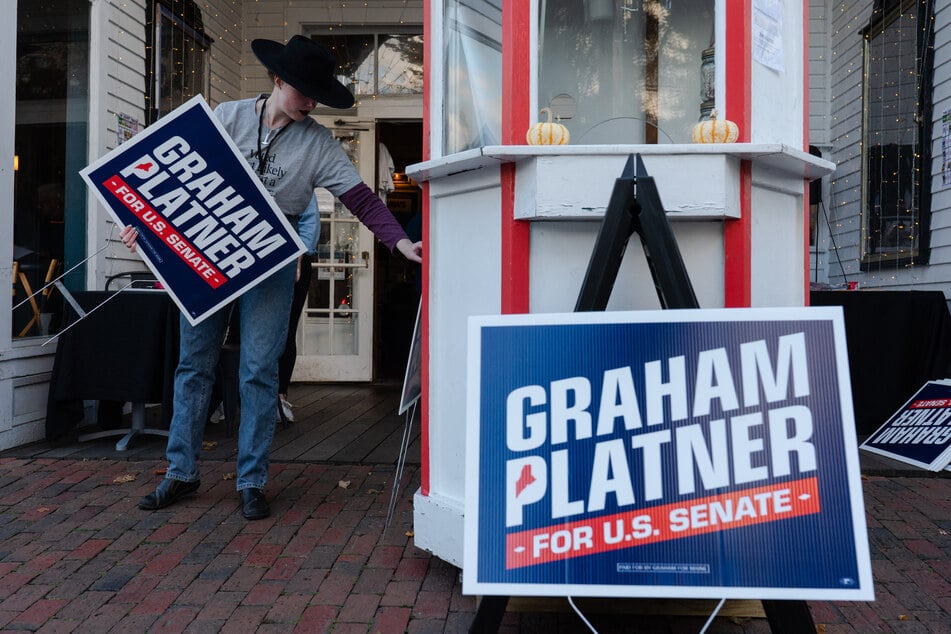 A volunteer sets up signs in support of Graham Platner's Senate campaign before a town hall at the Leavitt Theater in Ogunquit, Maine, on October 22, 2025.
