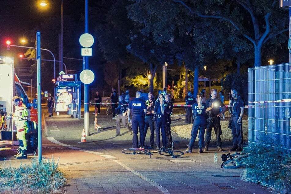Polizei und Rettungskräfte sind in Köln-Mülheim nach Schüssen auf offener Straße an einem Tatort beschäftigt.