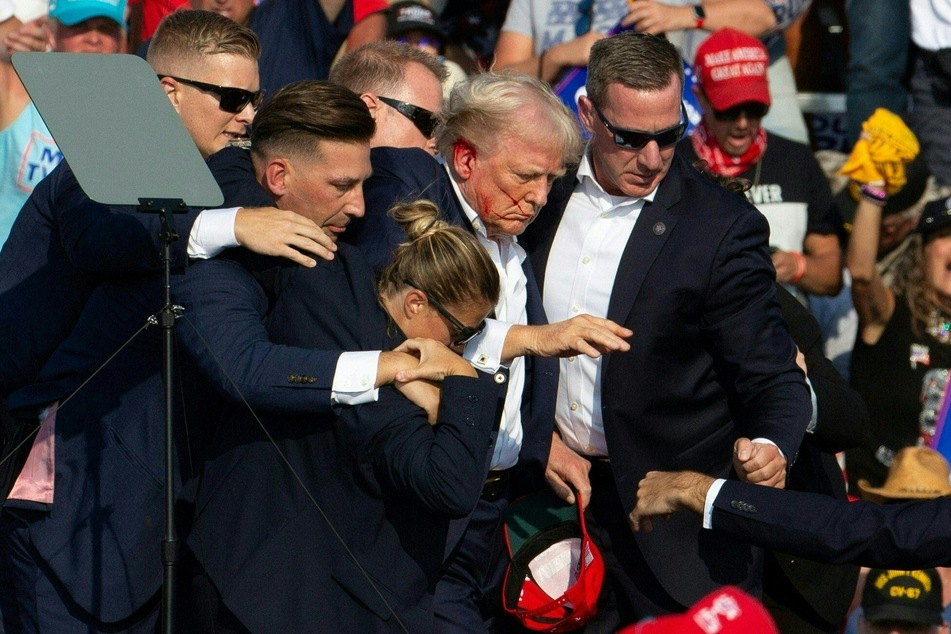 Republican candidate Donald Trump (c.) is seen with blood on his face surrounded by secret service agents as he is taken off the stage at a campaign event at Butler Farm Show Inc. in Butler, Pennsylvania on Saturday.