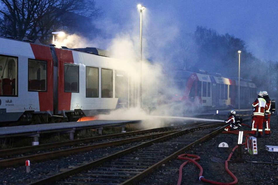 Feuerwehrleute löschen den brennenden Zug.