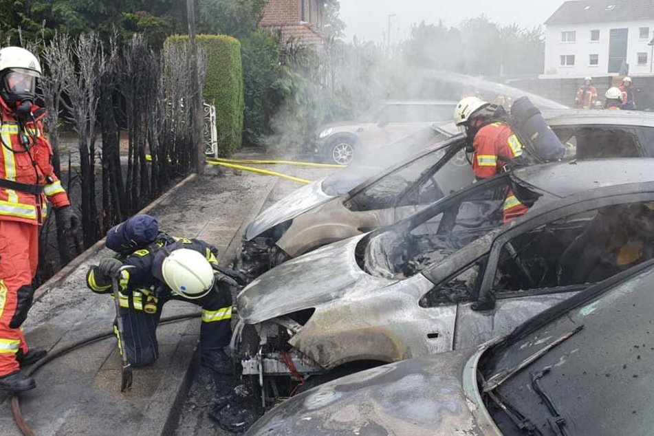 Feuerwehrleute in Velbert löschen den Brand bei dem drei Autos komplett ausgebrannt sind.