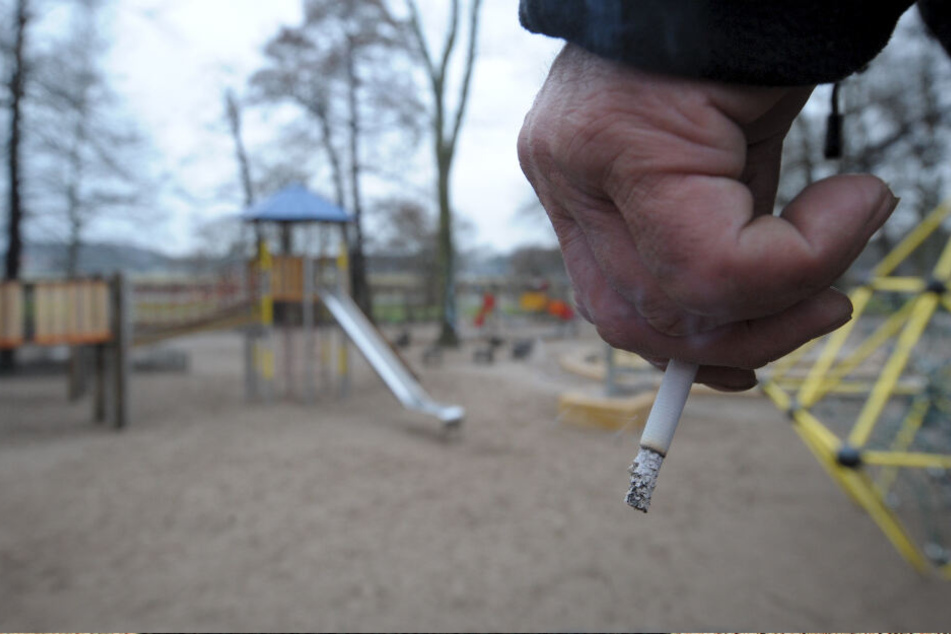 Ein Raucher blickt auf einen Spielplatz. (Symbolbild)