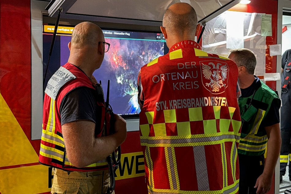 Einsatzkräfte betrachten auf einem Bildschirm Videobilder einer Drohne, die einen Waldbrand bei Zell am Harmersbach filmt.