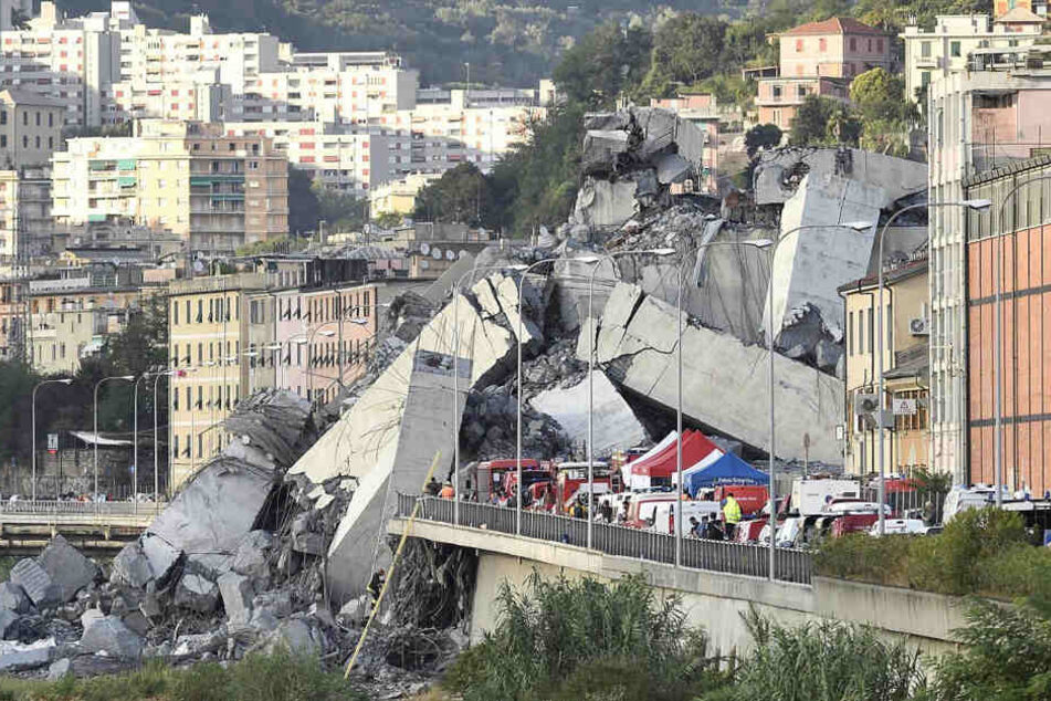 Fahrzeuge der Rettungskräfte sind vor der teilweise eingestürzten Autobahnbrücke Ponte Morandi zu sehen.