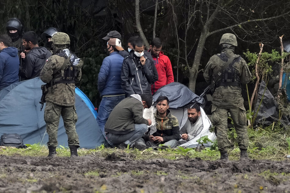Polnische Sicherheitskräfte umringen Migranten, die an der Grenze zu Belarus festsitzen.