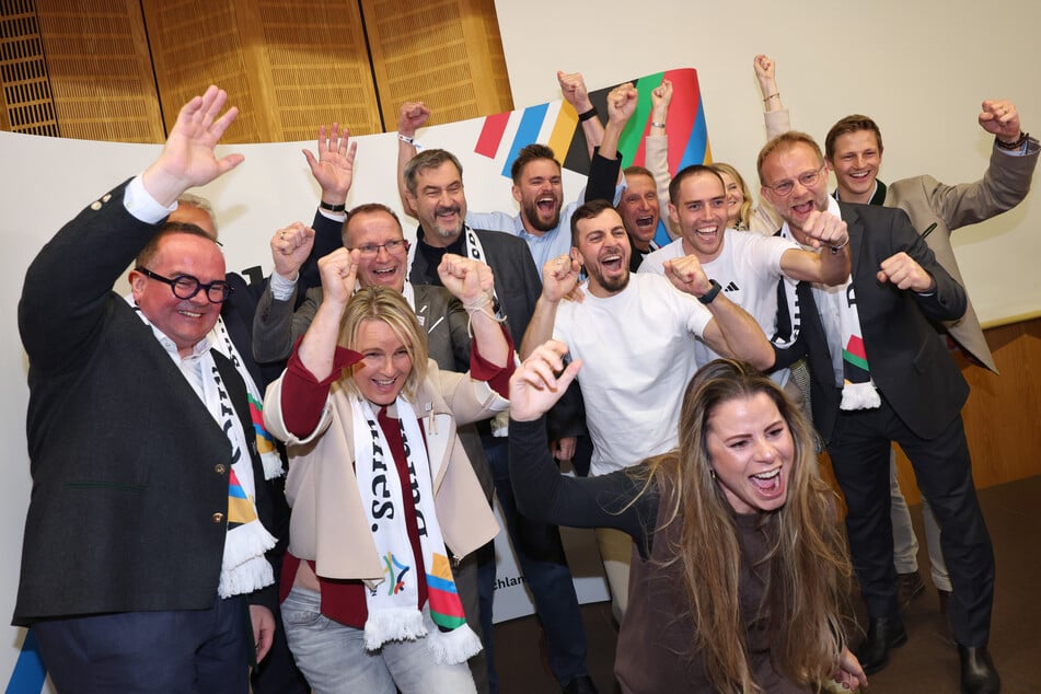 Bayerns Ministerpräsident Markus Söder (58) jubelt zusammen mit Sportlern, Politikern und Funktionären nach der ersten Hochrechnung.