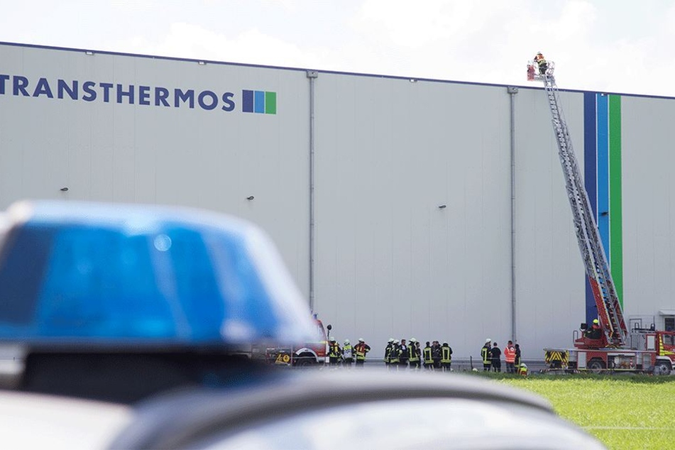 Feuerwehrleute stehen auf einer Teleskopleiter von der Lagerhalle in Dissen.