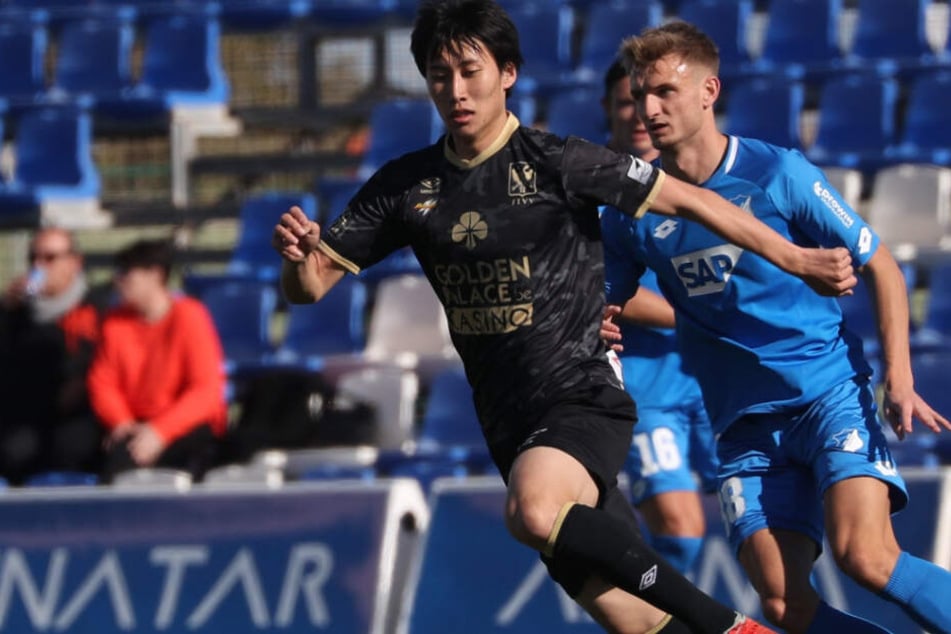 Daichi Kamada (22, links im Bild) kämpft in einem Testspiel für den belgischen Club VV St. Truiden gegen Hoffenheims Stefan Posch um den Ball.
