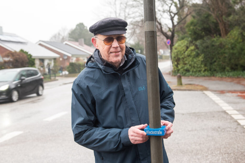 Volker König, Erfinder von Hilfsmitteln für Behinderte, steht an einem Straßenschild.