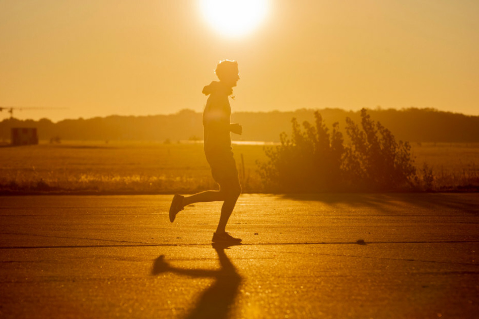 Ein Jogger rennt im Licht der Morgensonne über das Tempelhofer Feld.