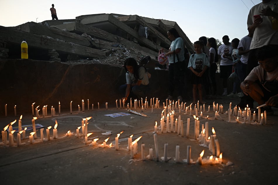 Relatives light candles during a mass for the victims in Caraballeda, Venezuela, on July 24, 2026, one month after an earthquake struck the area.