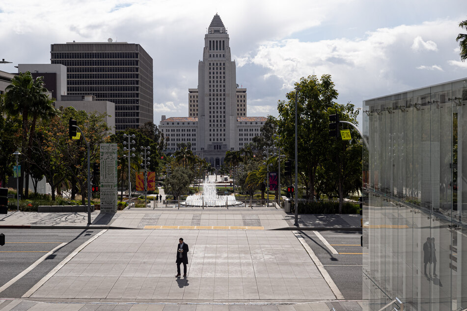 A pedestrian crosses the deserted Grand Avenue in front of the Los Angeles City Hall.