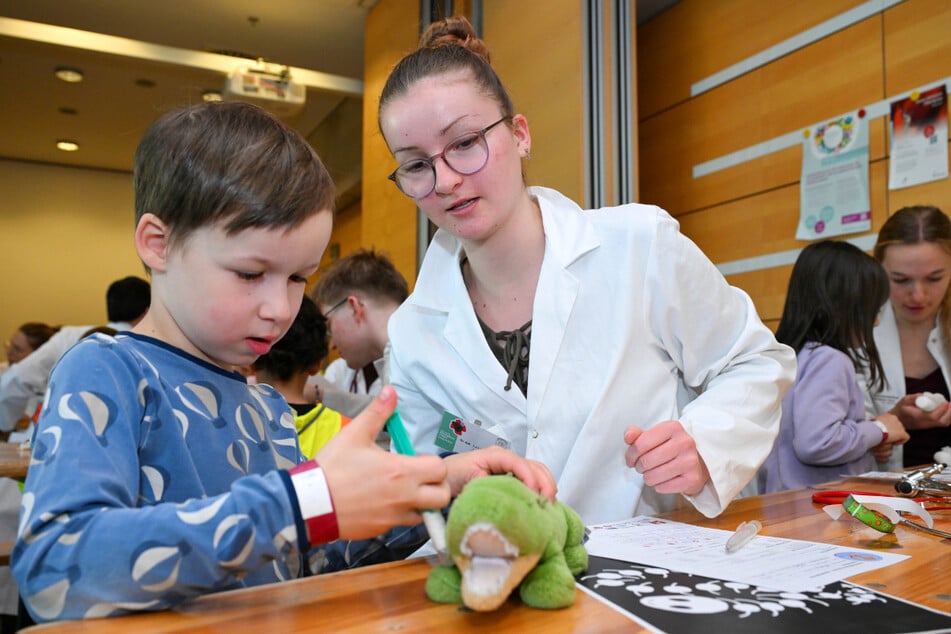 Henry (6) und die Medizinstudentin Martha Schauerte (19) behandeln das verletzte Plüschtier "Kroko" mit einer Spritze.