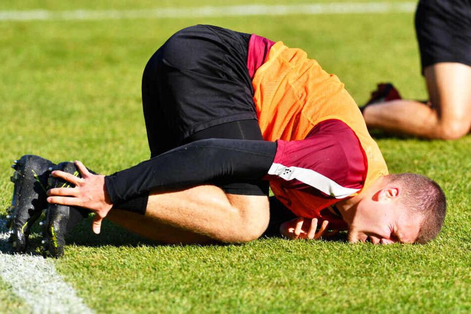 ...und mit schmerzverzerrtem Gesicht, sich den verletzten Knöchel haltend beim Training auf dem Rasen liegend.