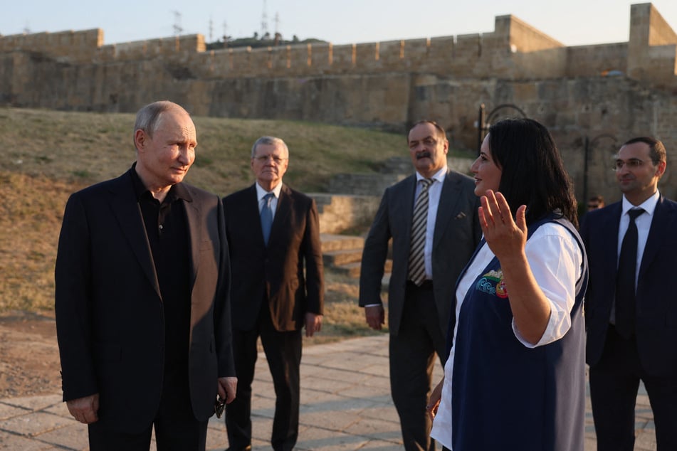 "Putin" besichtigt die uralte Burgruine von Naryn-Kala und hört der Touristenführerin aufmerksam zu.