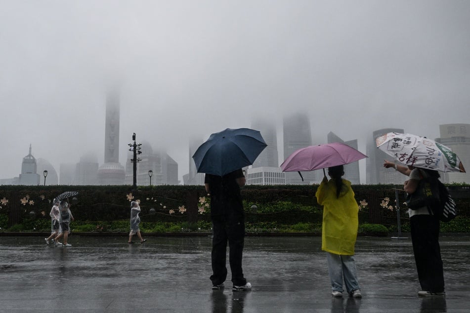 People protect themselves with disposable rain cover during the passage of Typhoon Co-May in Shanghai, China, on July 30, 2025.