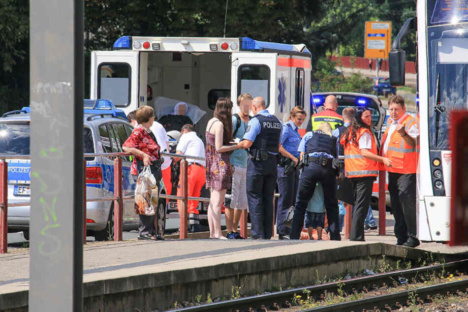 Polizisten nehmen Zeugenaussagen auf, während die Frau in einen Rettungswagen geschoben wird.