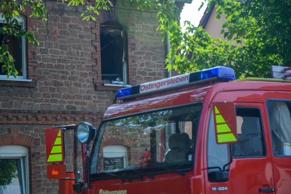 Rettungskräfte vor dem Haus in Erxleben bei Magdeburg. Über dem Fenster sind deutliche Rußspuren zu erkennen.