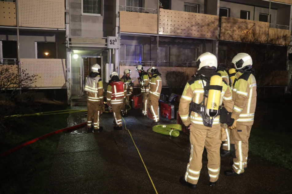 Feuerwehrleute stehen vor einem Wohnhaus Am Leutewitzer Ring.