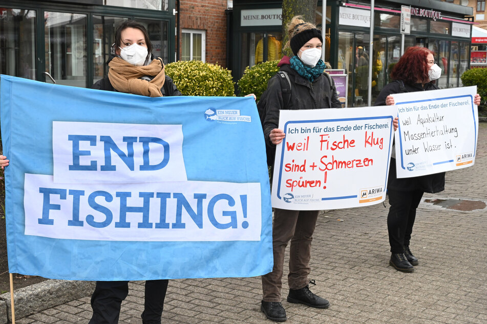 Auf der Demonstration "Ein neuer Blick auf Fische" hält eine Teilnehmerin eine Fahne mit dem Schriftzug "End Fishing!" hoch.