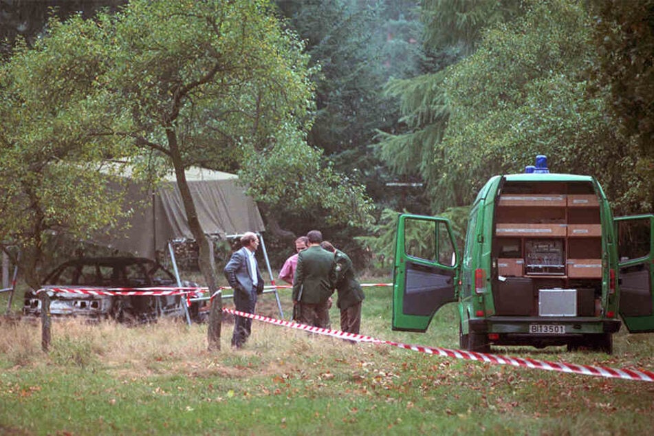 Polizeibeamte bei der Spurensuche auf einem Waldparkplatz.
