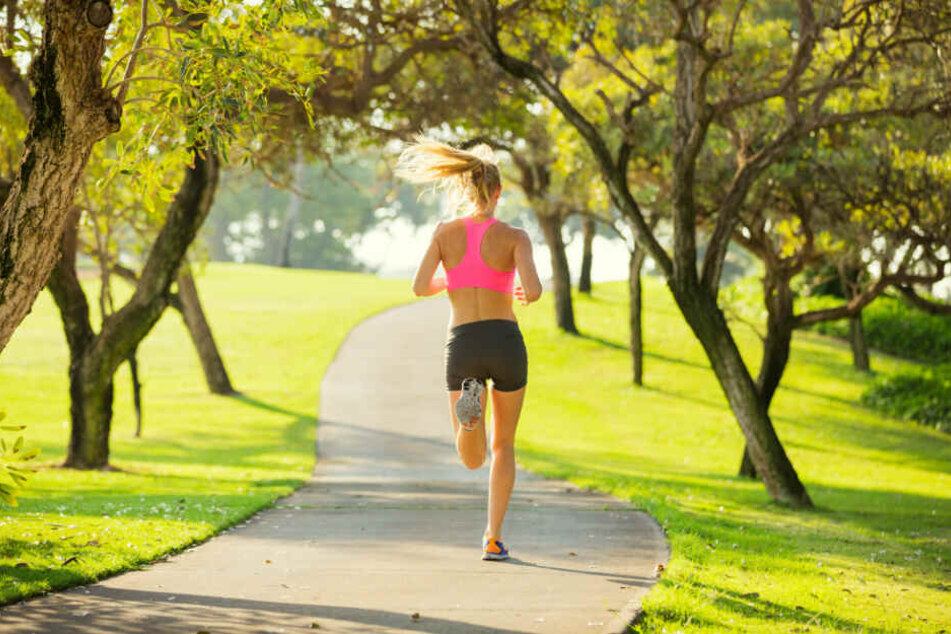 Eine Joggerin läuft durch einen Park. (Symbolbild)