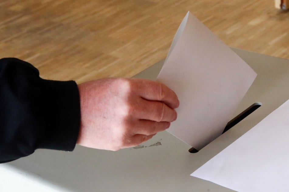 Eine Wählerin wirft ihren Wahlschein in eine Urne ein (Symbolbild)