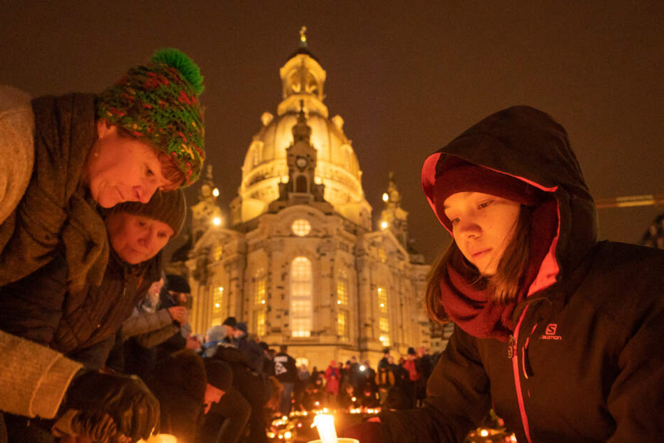 Dresdner zünden auf dem Neumarkt Kerzen an. Im Hintergrund die Frauenkirche.