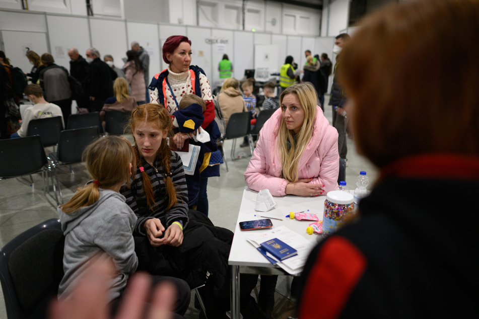 Oksana (r.) aus Saporischschja und Lubmila (stehend) aus Odessa warten mit ihren Kindern im Ankunftszentrum für geflüchtete Menschen aus der Ukraine in der Messe Dresden.
