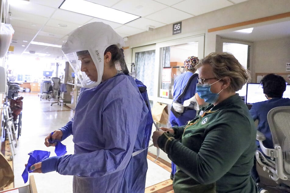 Deb Dalsing (r), Stationsleiterin einer Klinik in Madison, hilft der Krankenpflegerin Ainsley Billesbach beim Anziehen der Schutzkleidung. Bis vor kurzem hatte das Universitätsklinikum UW Health vier Flügel für Corona-Patienten. Um der wachsenden Nachfrage gerecht zu werden, wurde ein weiterer hinzugefügt.