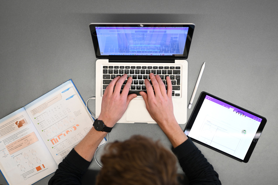 Ein Lehrer für Mathematik und Spanisch unterrichtet im Lehrerzimmer am Laptop.