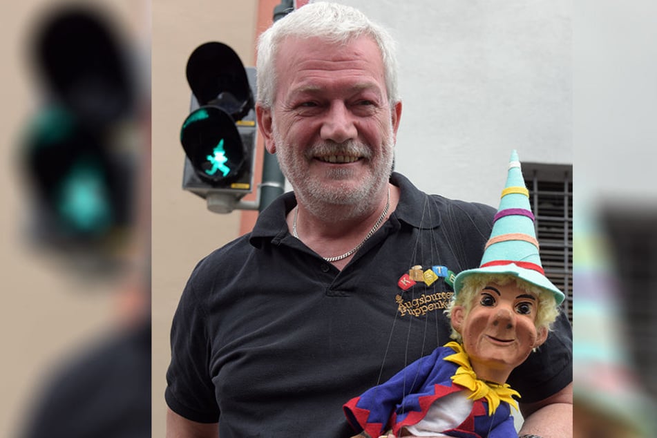 Der Leiter der Augsburger Puppenkiste, Klaus Marschall mit der Marionette Kasperl an einer Ampel.