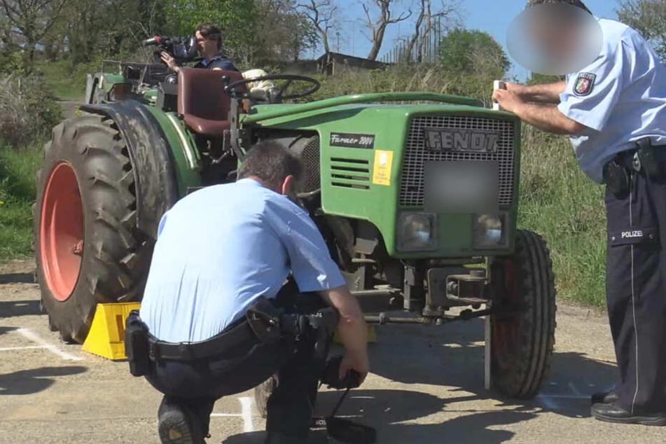 Polizisten untersuchen den Traktor, der den 82-Jährigen schwer verletzte.