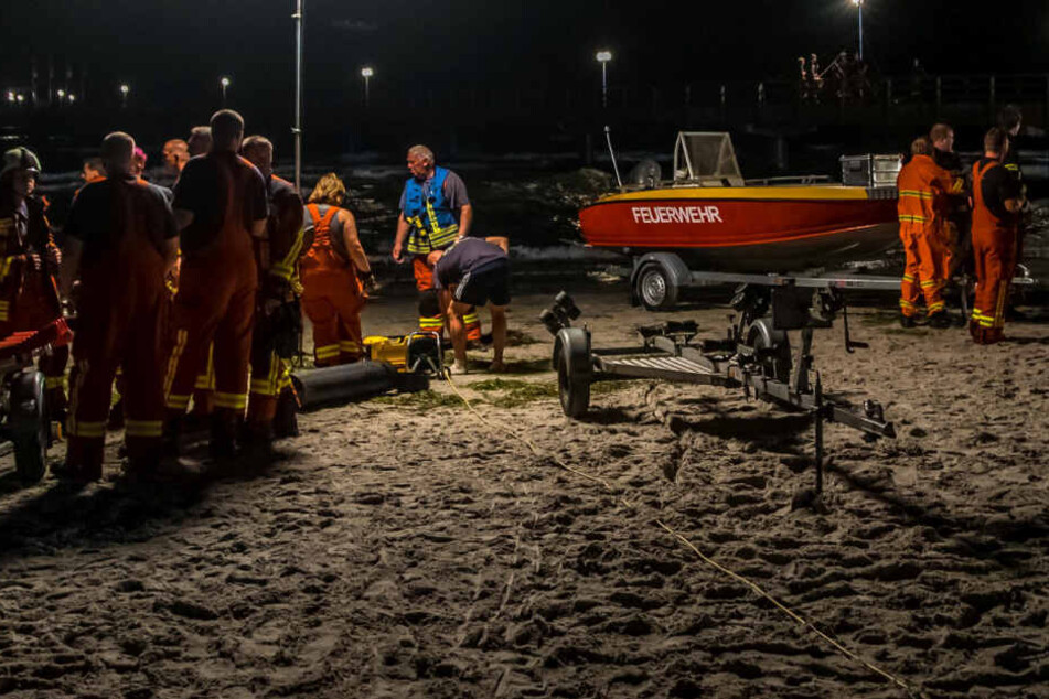 Rettungskräfte beraten sich am Sonntagabend am Strand von Scharbeutz.