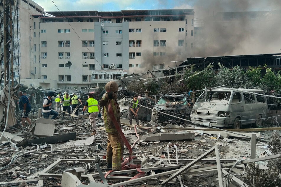 Rettungskräfte arbeiten an der Stelle eines israelischen Luftangriffs, der ein Gebäude getroffen und ein Krankenhaus beschädigt hat (im Hintergrund).