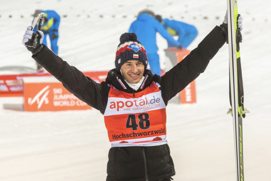 Der Pole Kamil Stoch jubelt nach der Siegerehrung und hält seinen Pokal in der Hand.