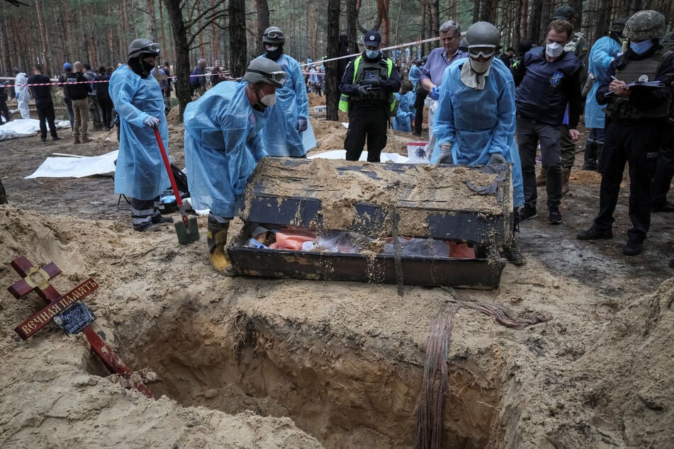 Forensic experts exhume bodies discovered in mass graves in Izyum.