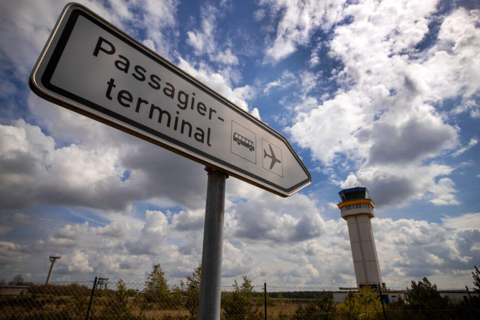 Ein Wegweiser zum Passagierterminal steht vor dem Tower am Flughafengelände.