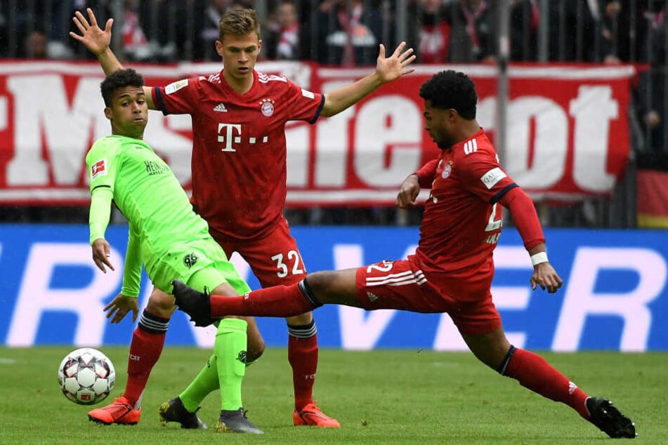Münchens Joshua Kimmich (M) und Serge Gnabry (r) kämpfen mit Linton Maina um den Ball.