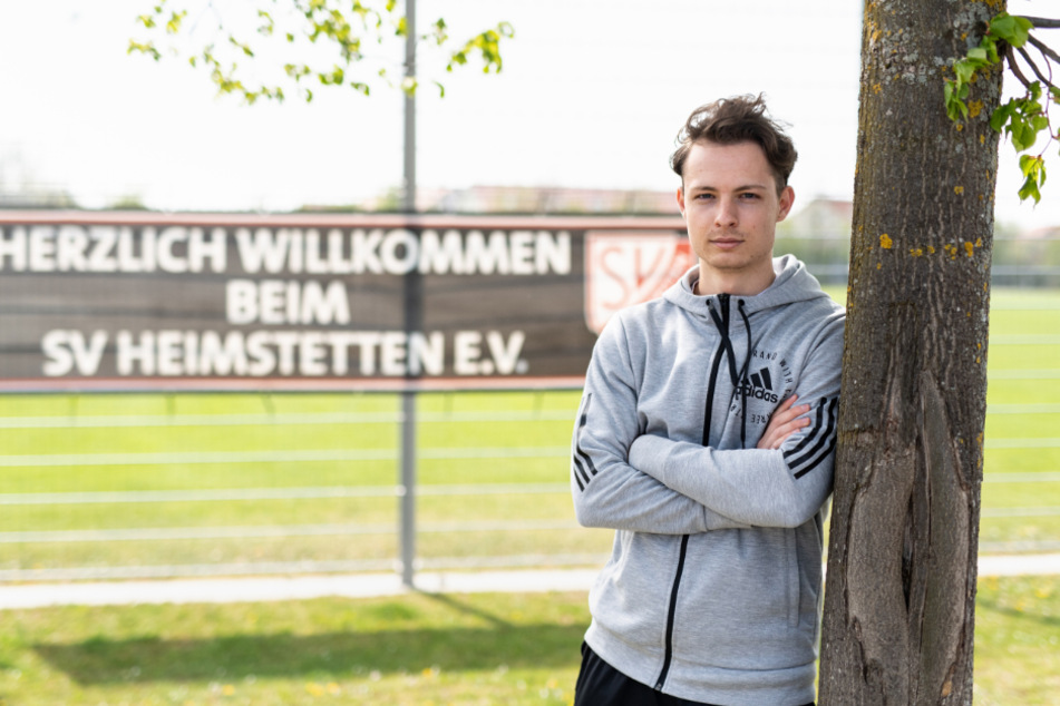 Luca Beckenbauer (19), Fußballspieler beim SV Heimstetten, blickt vor dem Trainingsgelände des Vereins in die Kamera.