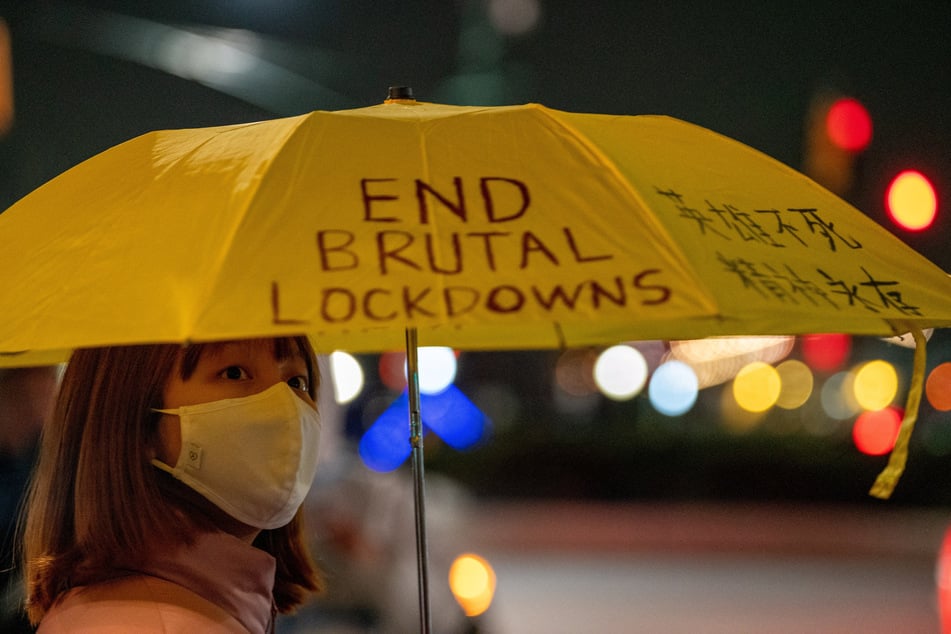A person holding an umbrella with an "End Brutal Lockdowns" slogan on it takes part in a protest near the Chinese consulate in New York City.