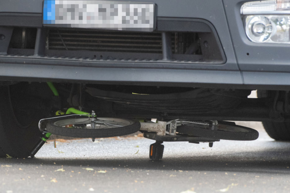 Ein Kinderfahrrad liegt unter der Vorderachse dss Lkw.