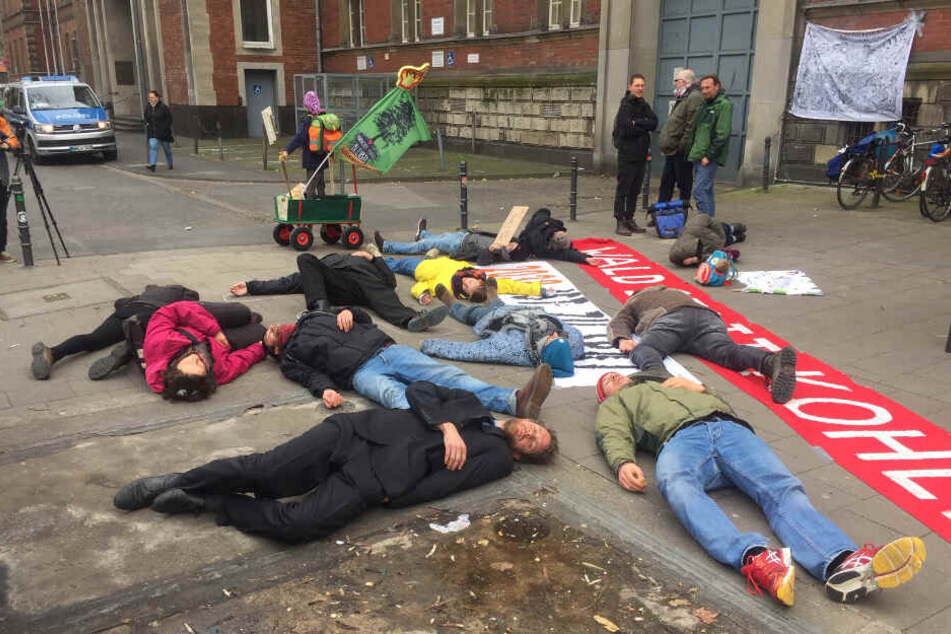 Aktivisten stellen sich vor dem Verwaltungsgericht tot. Auf dem Banner steht "Wald statt Kohle".