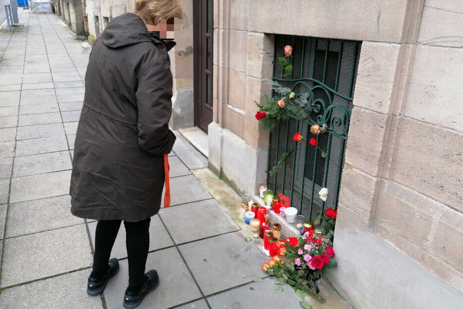 Eine Frau bleibt an der Stelle stehen, an der mittlerweile Kerzen und Blumen an das Opfer erinnern.