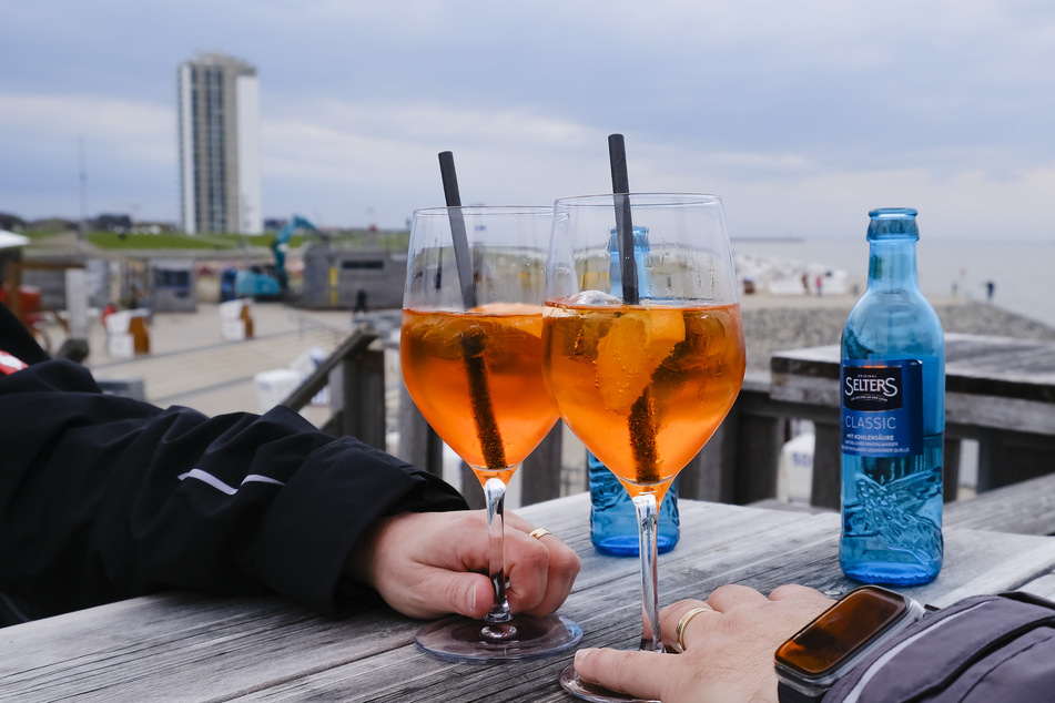 Zwei Urlauber in Büsum stoßen mit ihren Gläsern an.